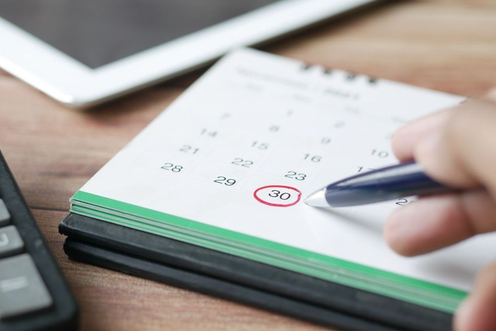 Hand markiert einen Termin im Tischkalender