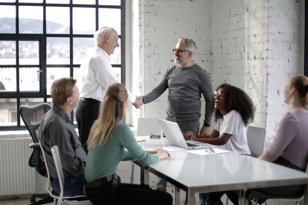 Mehrere Menschen arbeiten gemeinsam an einem Tisch in einem hellen Büro